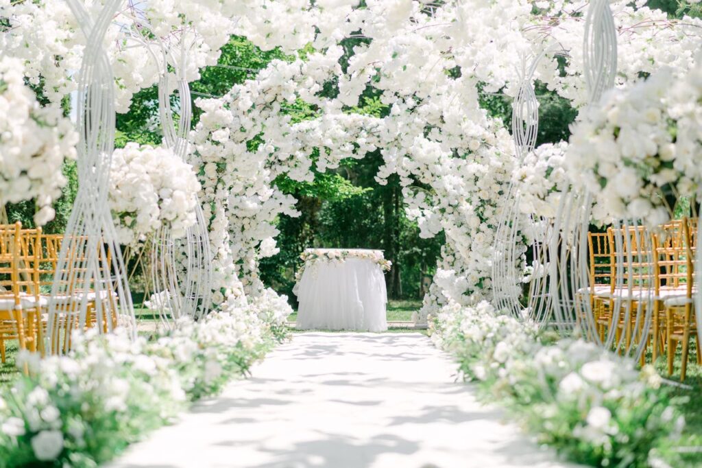 Magnifique cérémonie laïque dans un jardin avec une allée blanche et des fleurs monochromes.